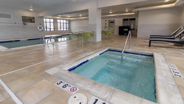 Piscina interna com água cristalina, linhas de profundidade marcadas e placa de salva-vidas.