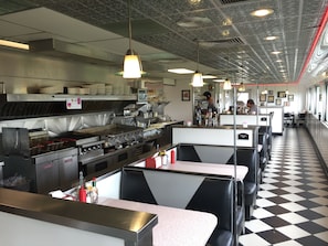 A diner with booths, a kitchen area, and a checkered floor.