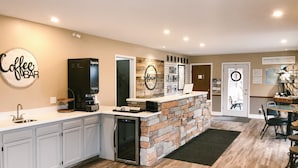 Una cocina moderna con barra para café, encimera de piedra y refrigerador.