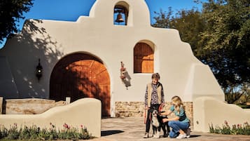 Stunning historic building with a bell tower and arched doorways, set amidst a beautifully landscaped garden.