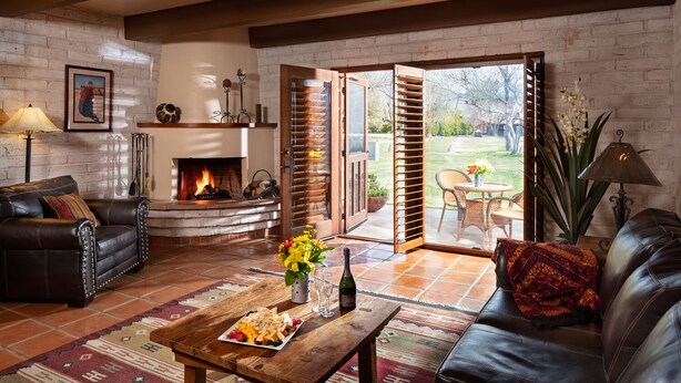 A cozy living room with a fireplace, leather sofas, a coffee table with snacks, and a view of the outdoors. - Tubac Golf Resort & Spa (Tubac)