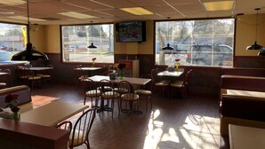 Ein Restaurantinneres mit Tischen, Stühlen und einem Fernseher an der Wand.