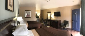 A hotel room with two beds, a desk, a chair, a TV, and a door. - Valueinn Eugene - Airport  (Eugene)