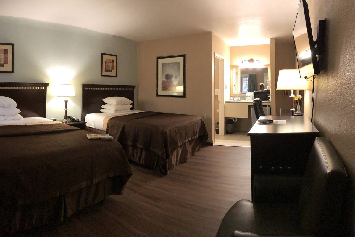 Une chambre d’hôtel avec deux lits, un bureau et une télévision.