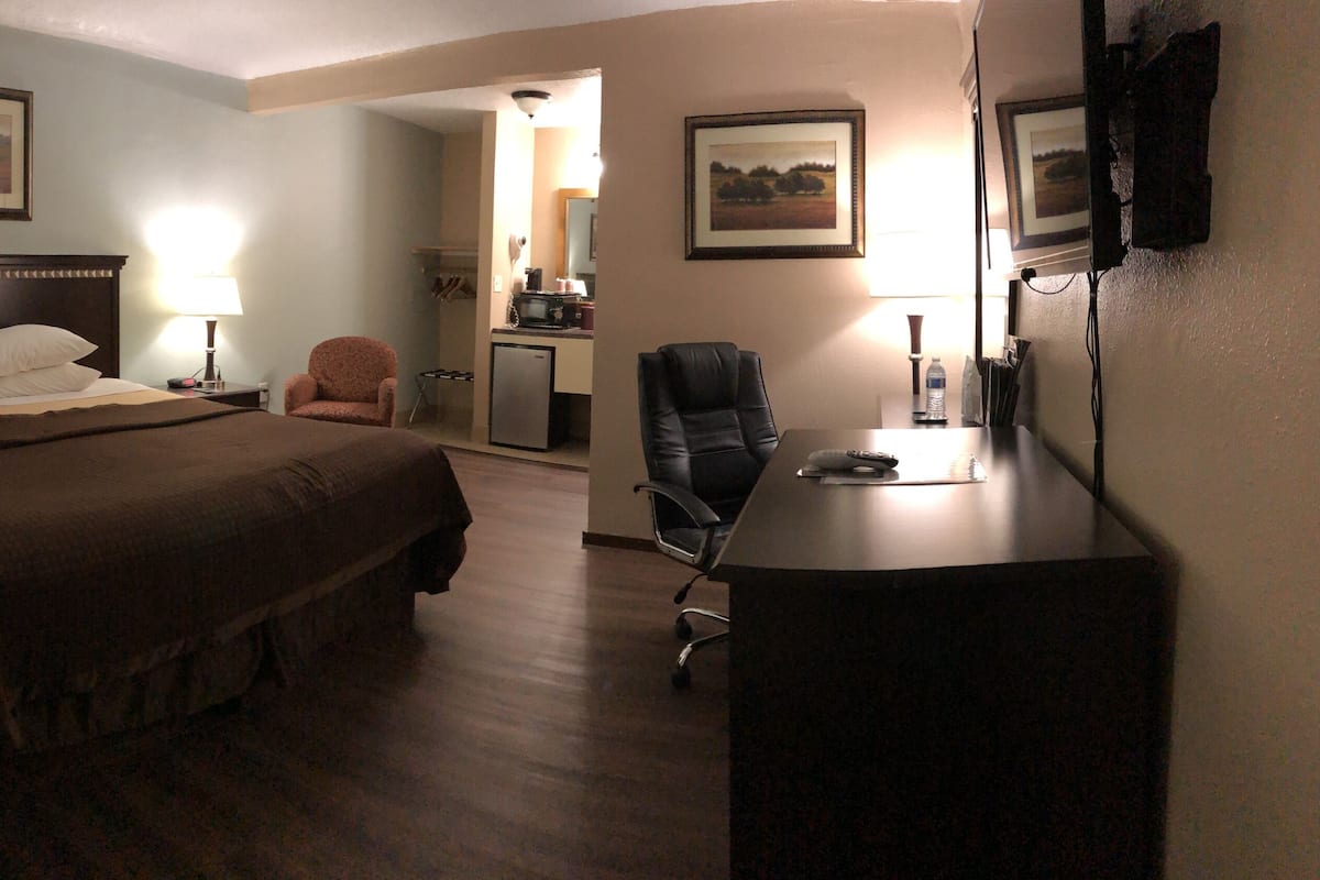 Une chambre d’hôtel avec un grand lit, un bureau, une chaise et une kitchenette.