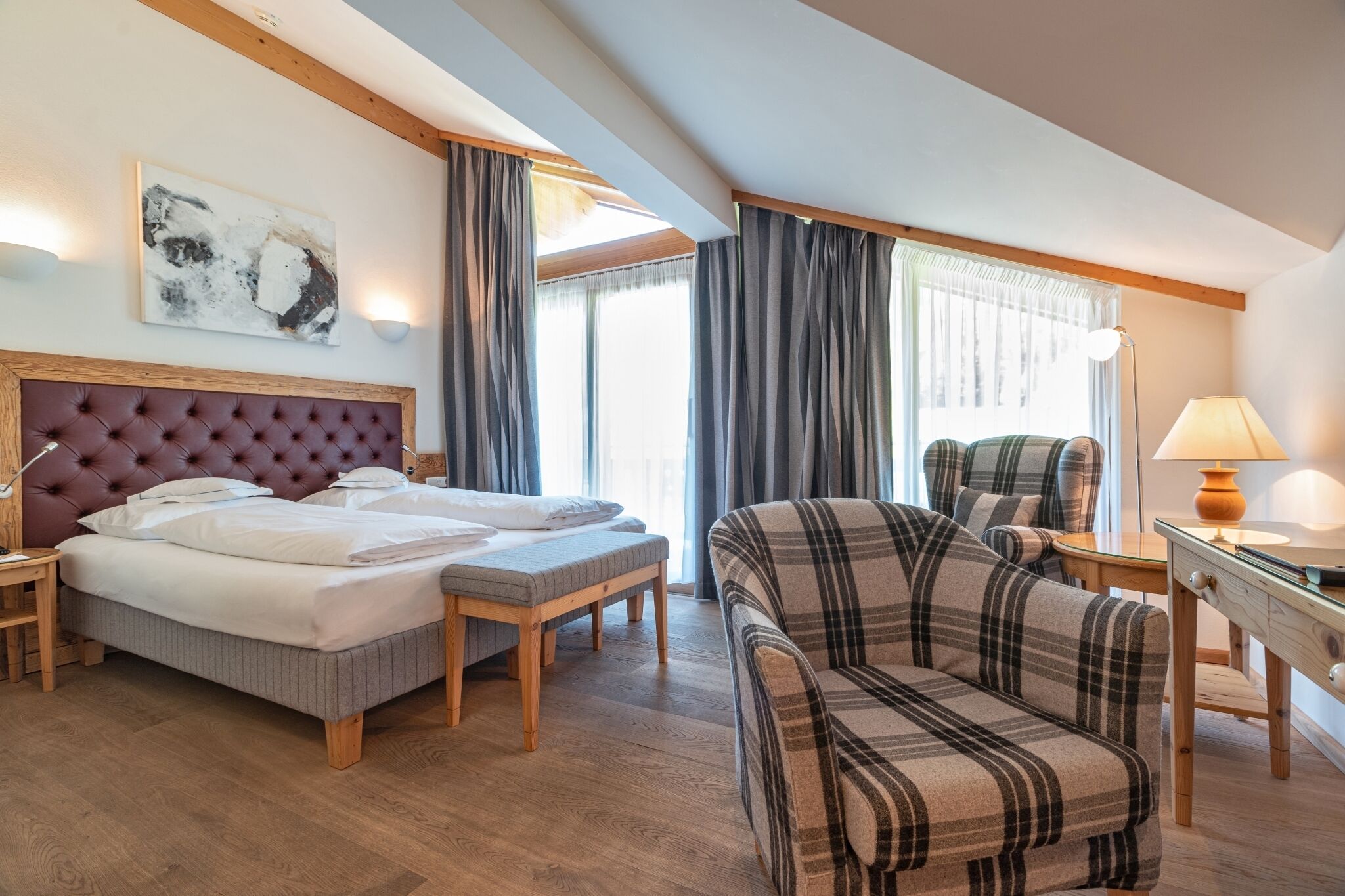 Une chambre d’hôtel avec un lit, un banc, un canapé, un bureau et une lampe.