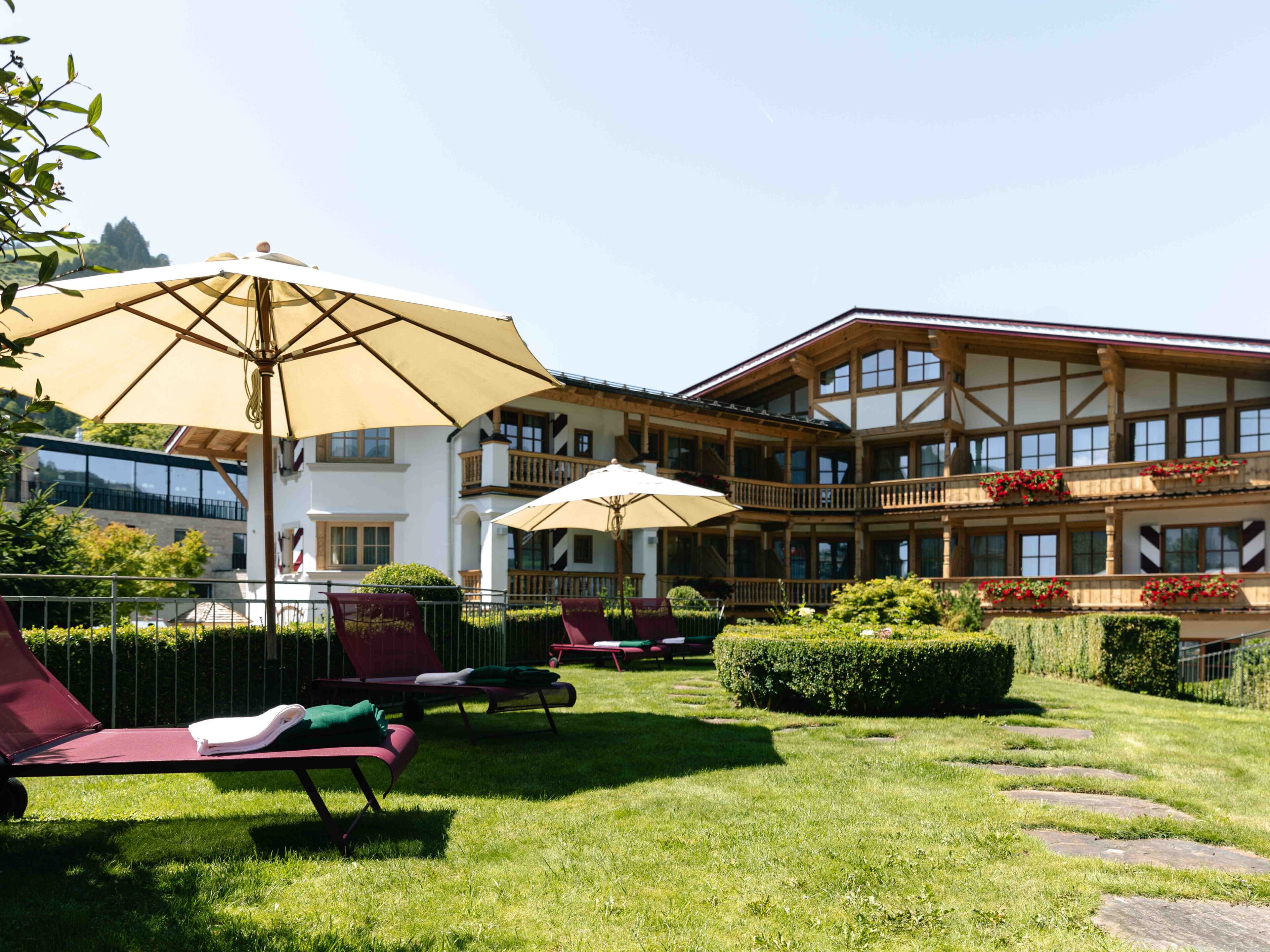 A hotel with outdoor seating, a large building with multiple balconies, and a well-maintained lawn.