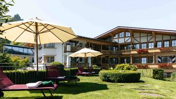 A hotel with outdoor seating, a large building with multiple balconies, and a well-maintained lawn.