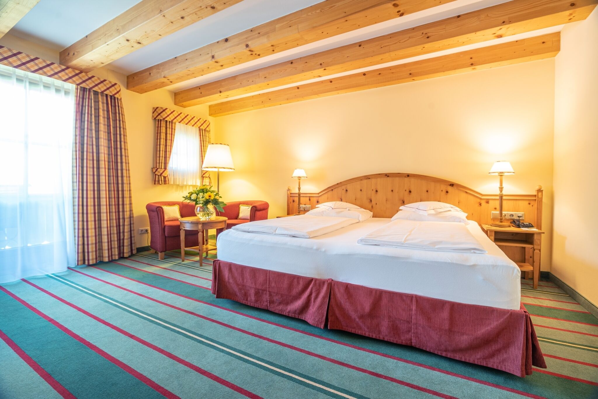 Ein Hotelzimmer mit einem großen Bett, zwei Nachttischlampen, einem Schreibtisch und einem Stuhl.