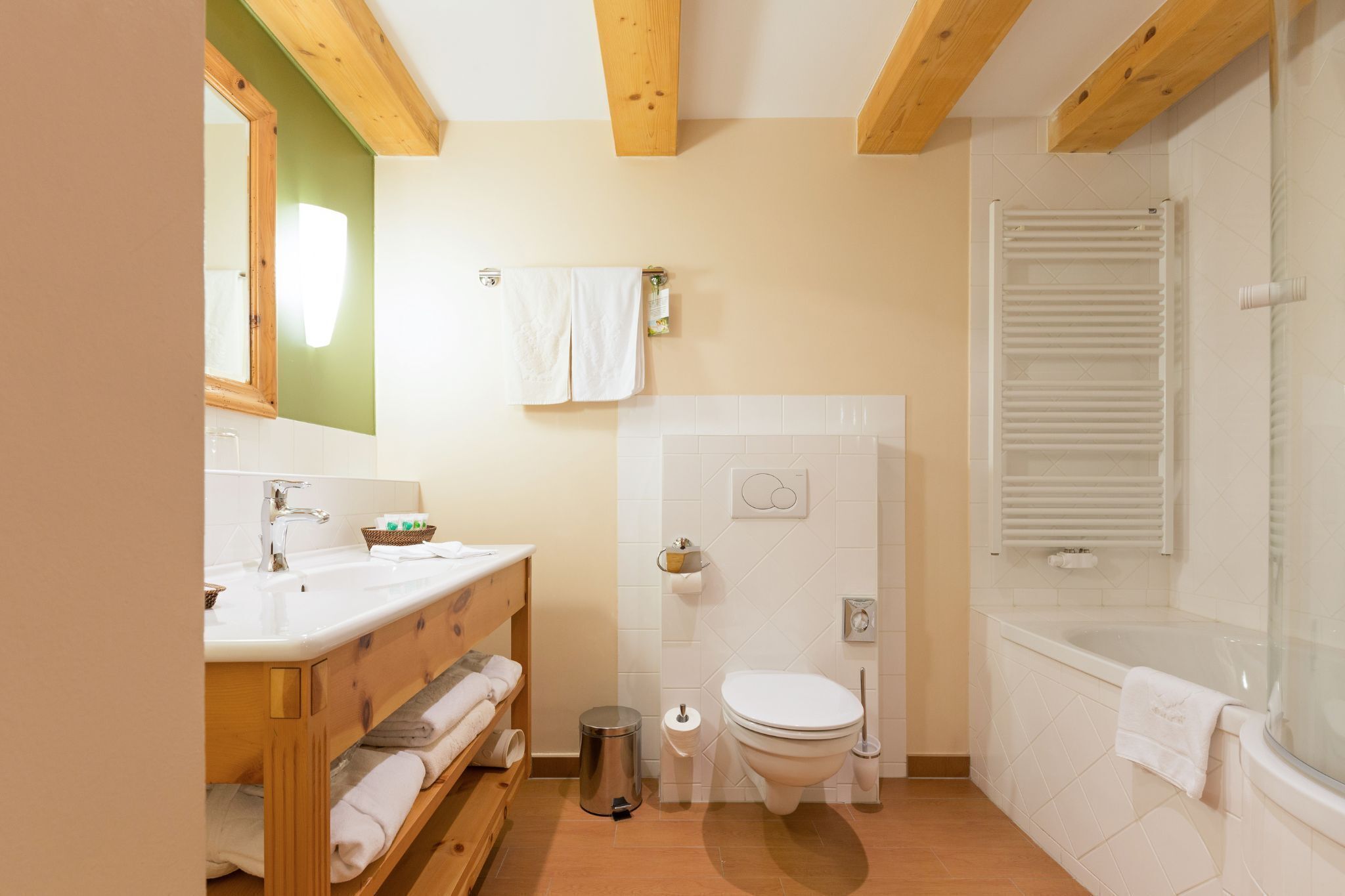 Une salle de bain avec un meuble-lavabo en bois, des toilettes, une douche et un porte-serviettes.