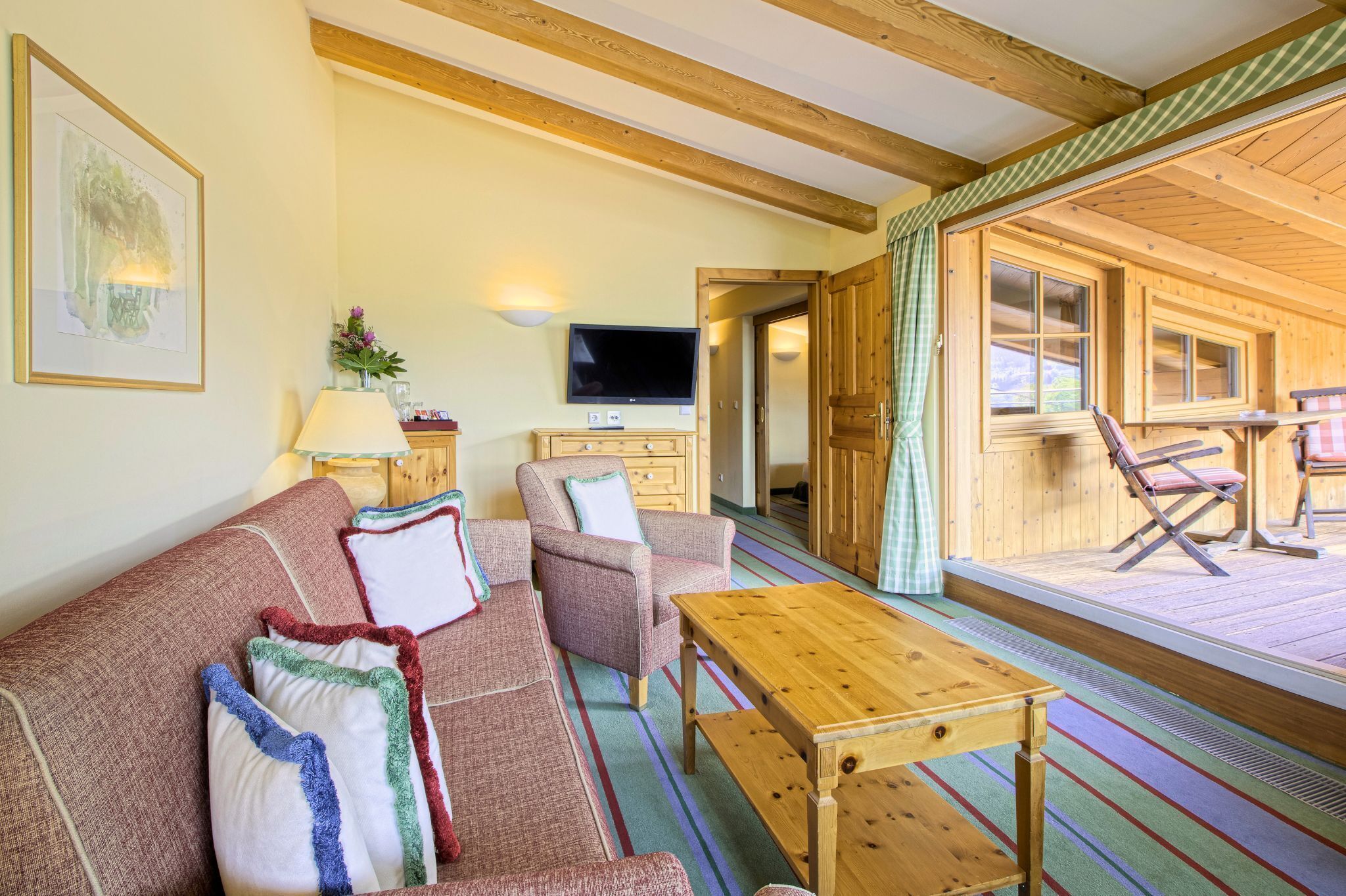 Una habitación acogedora con sofá, sillón, mesa de centro de madera y televisor.