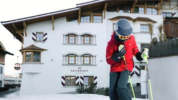Una persona con chaqueta y casco rojo parada frente a un edificio con el letrero 'KAISERHOF'.