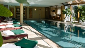 An indoor swimming pool with lounge chairs and potted plants. - Hotel Kaiserhof Kitzbuehel (Kitzbuhel)