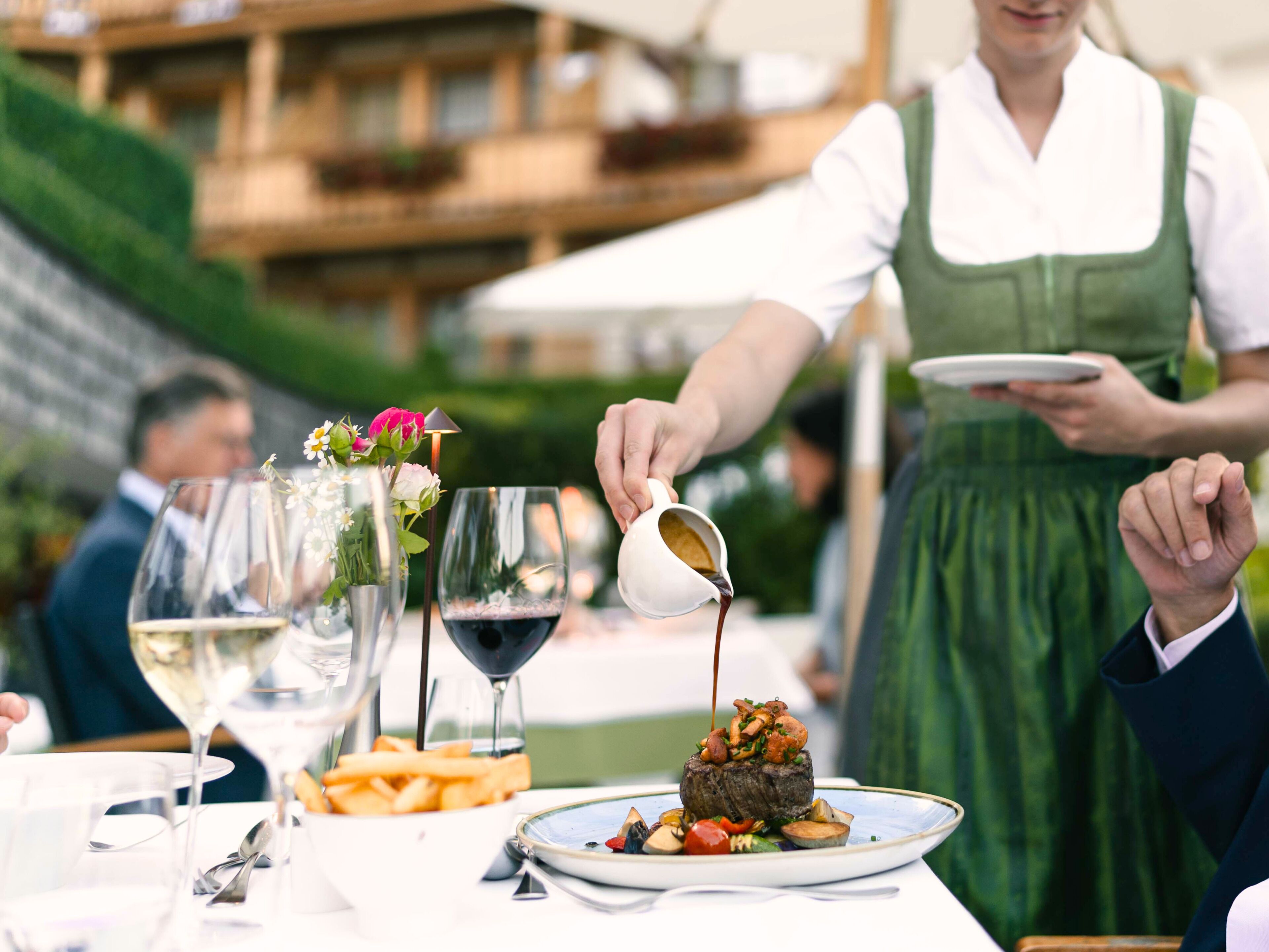 A dining table with a steak dish, a glass of red wine, and a white wine glass.