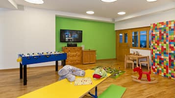 Playful space for kids with a foosball table, table tennis table, and colorful play mat.