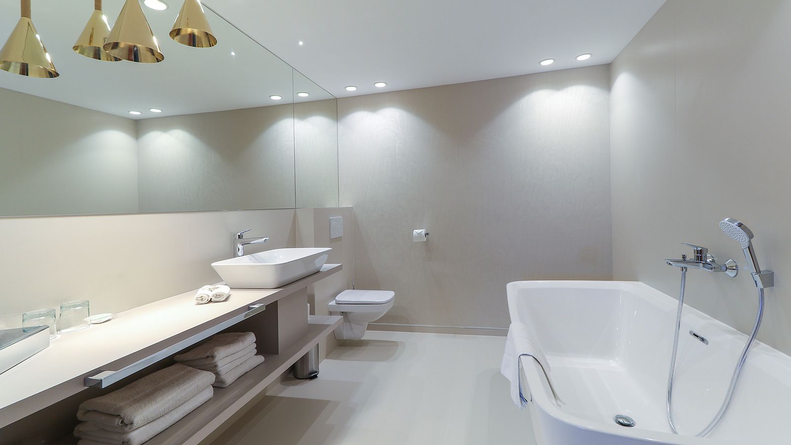 A modern bathroom with a large bathtub, a vanity with a sink, and a toilet.