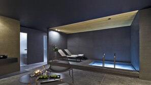 A modern spa room with a seating area, a massage table, and a large bathtub. - Hotel Karpatia (Humenne)