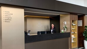 En hotellreception med en digital informationsskärm som visar en lista över rum, restaurang, barer, konferenslokaler, spa och träningsanläggning.
