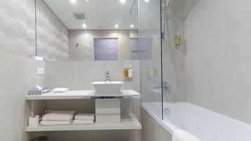 A modern bathroom with a glass-enclosed shower, a white sink, and a mirror above the sink.