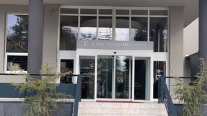 En modern hotellentrél med en glasfasad, en skylt med texten ”Hotel Karpatia” och en skylt med texten ”arbete och avkoppling” nedanför.