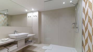 A modern bathroom with a large mirror, a white sink, and a shower area.