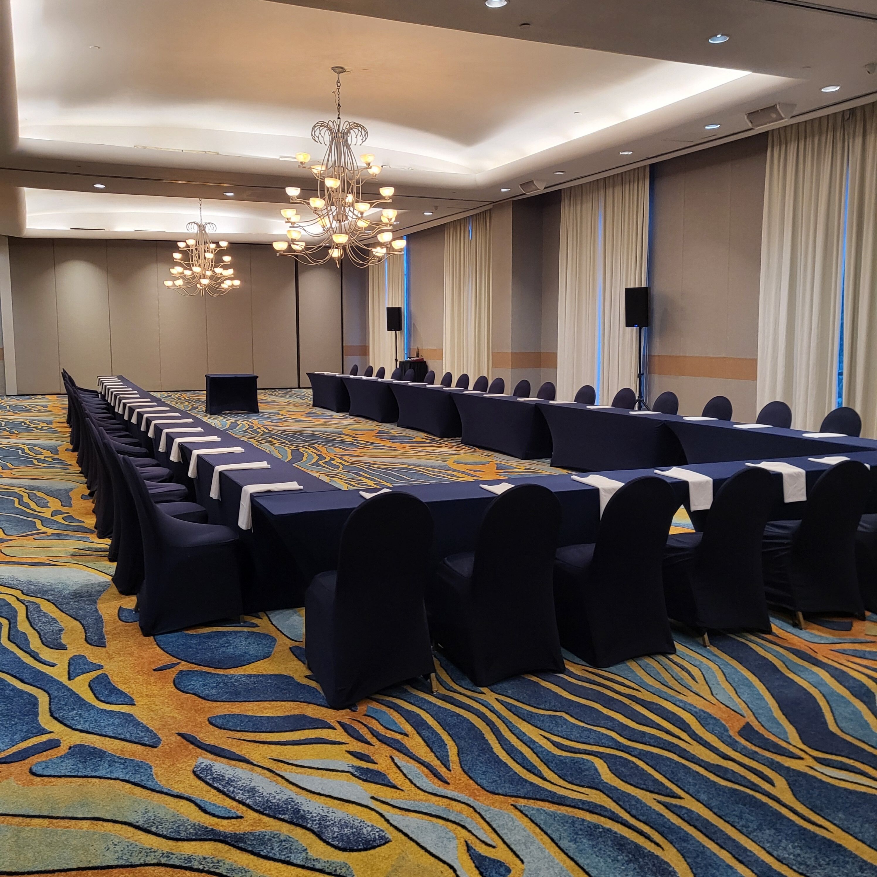 A conference room with a long table, chairs, a chandelier, and a patterned carpet.