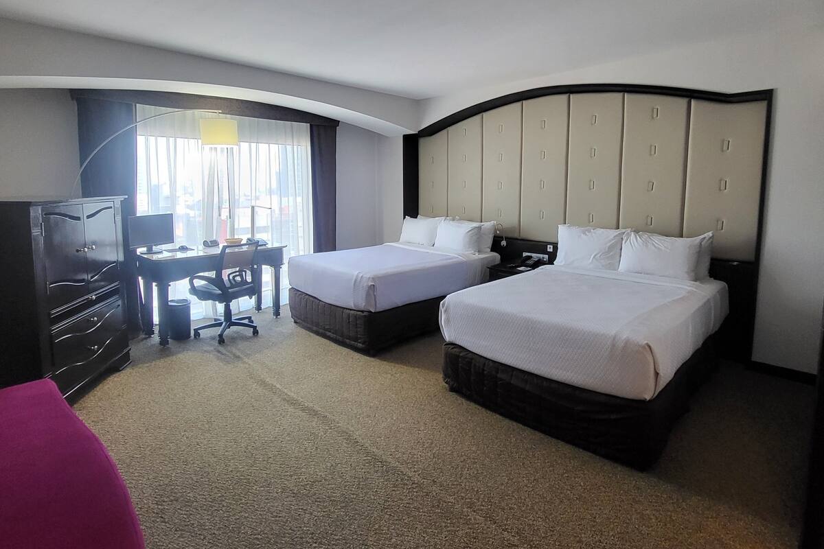 Una habitación de hotel con dos camas, un escritorio y televisión.