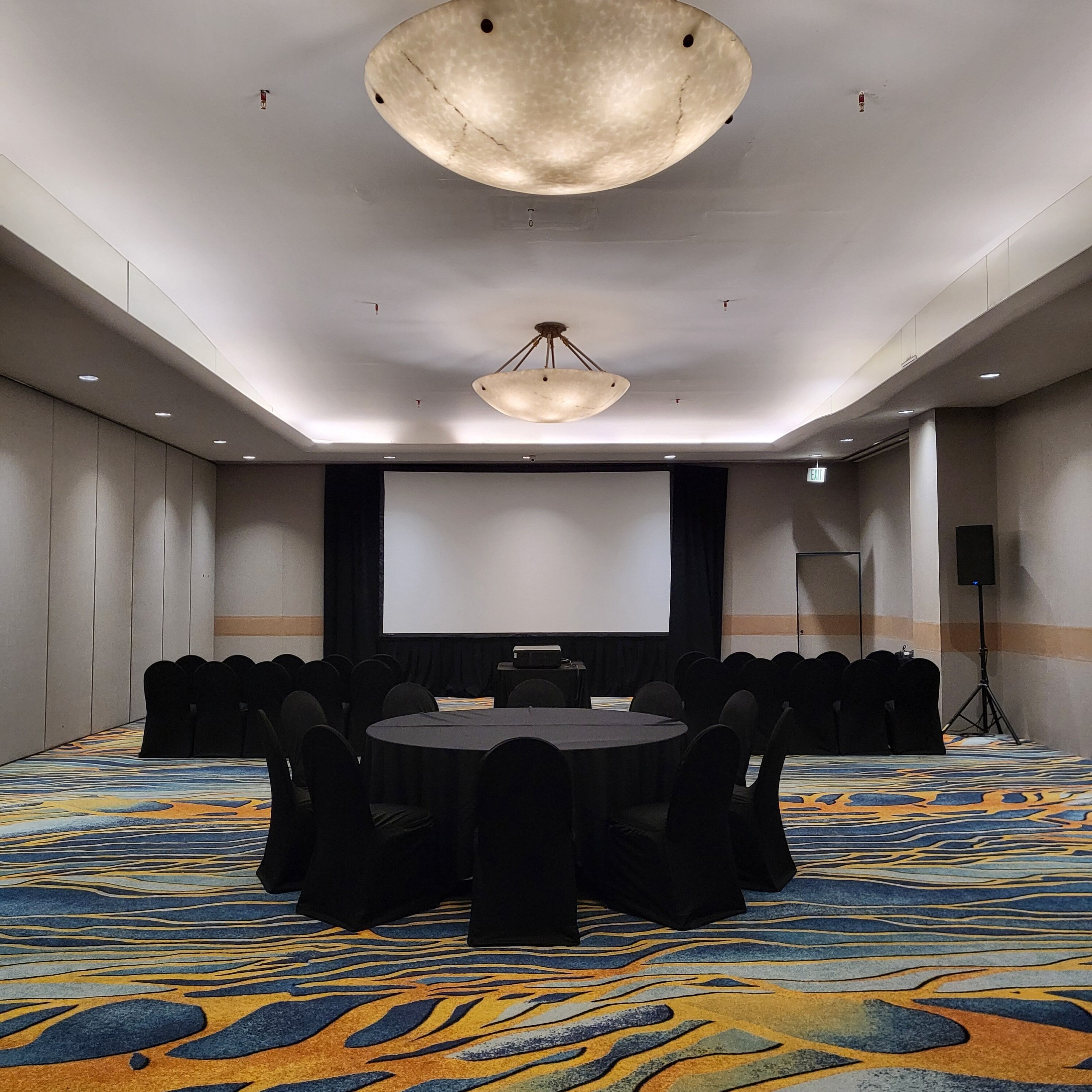 Une salle de conférence équipée d’un grand écran, de tables rondes et de chaises.