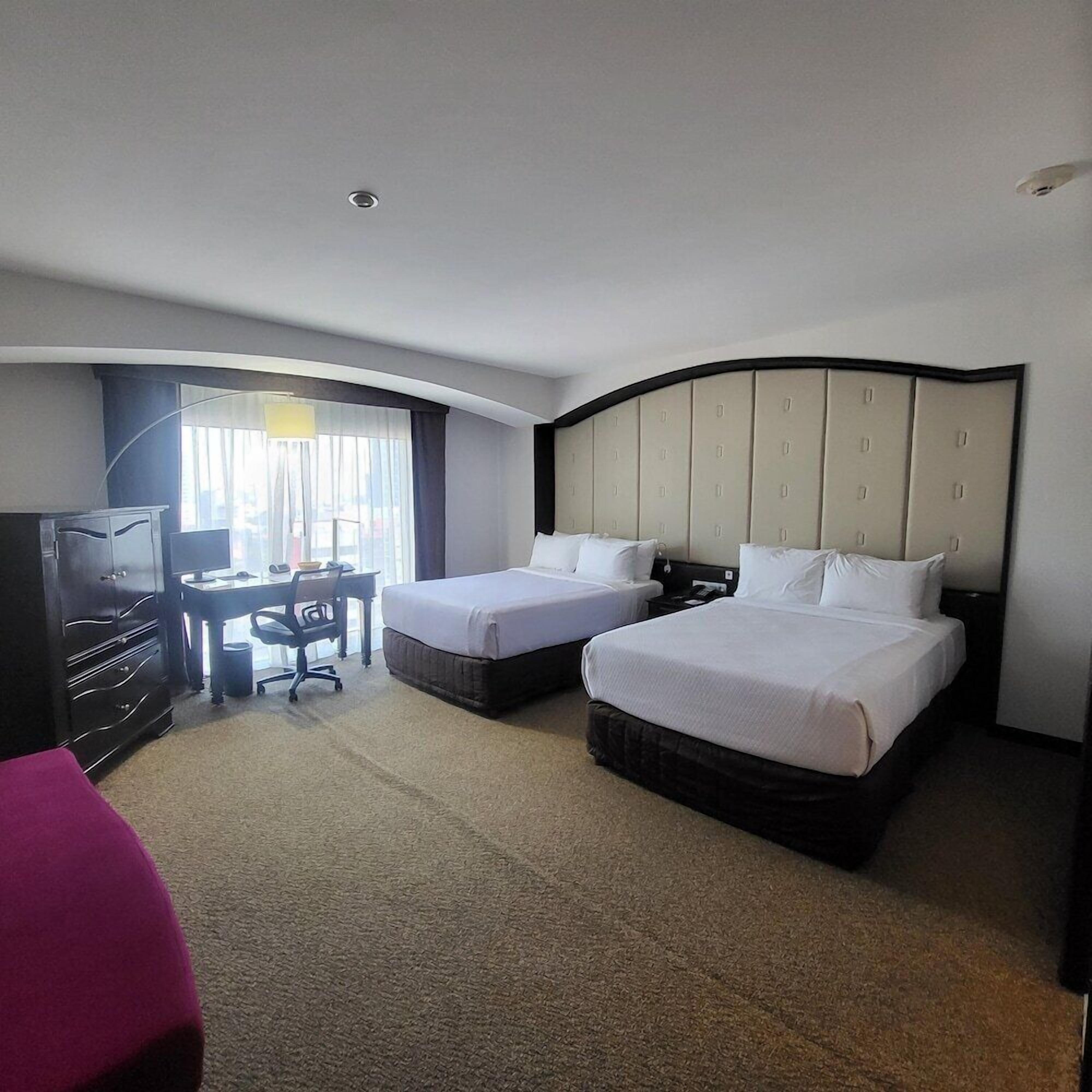 Habitación de hotel con dos camas, un escritorio y una televisión.