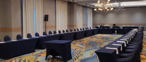 A conference room with a long table, chairs, and a patterned carpet.