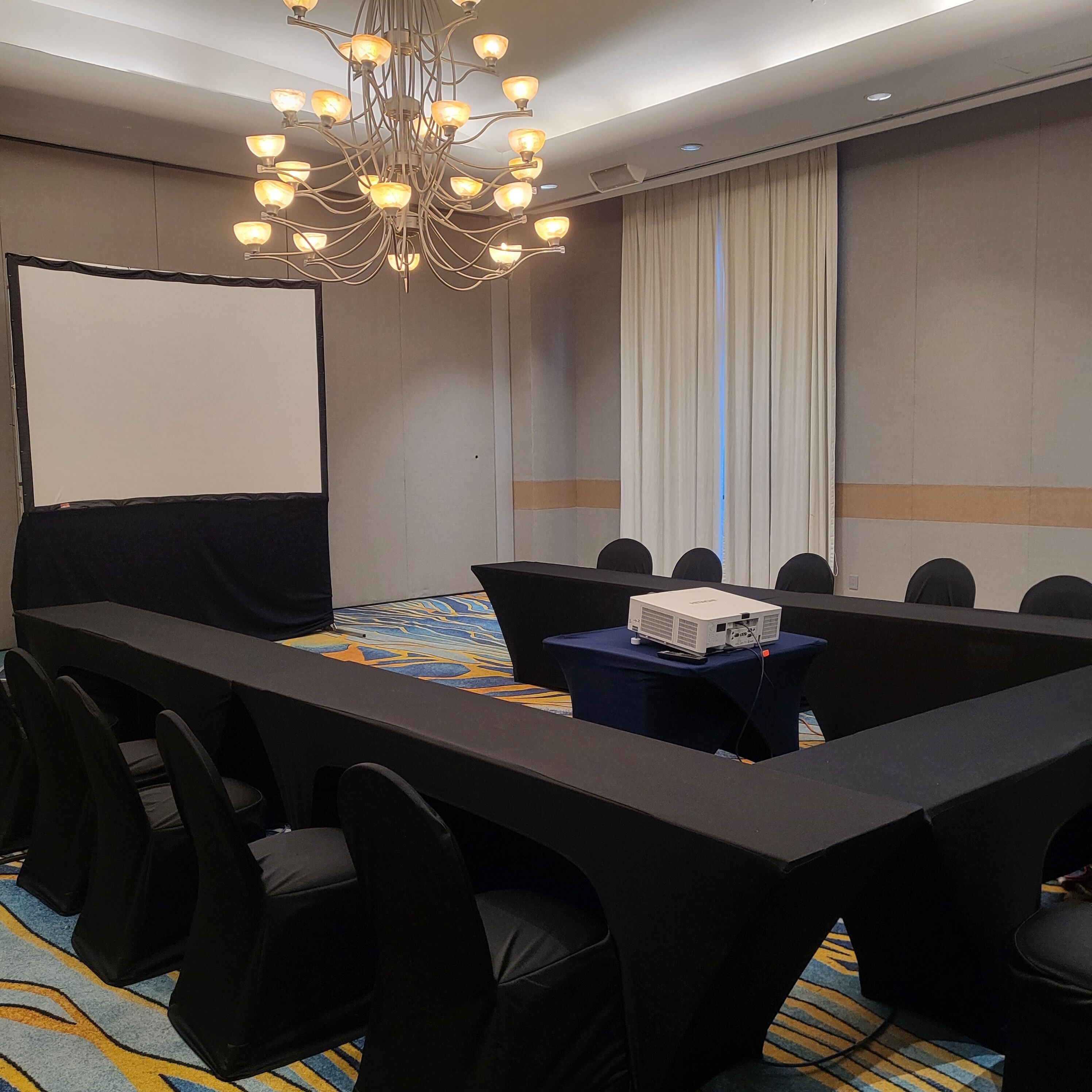 Une salle de conférence équipée d’une longue table, de chaises, d’un projecteur et d’un écran.