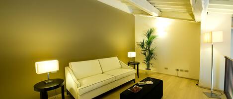 A living room with a sofa, two side tables with lamps, a coffee table, and a potted plant.