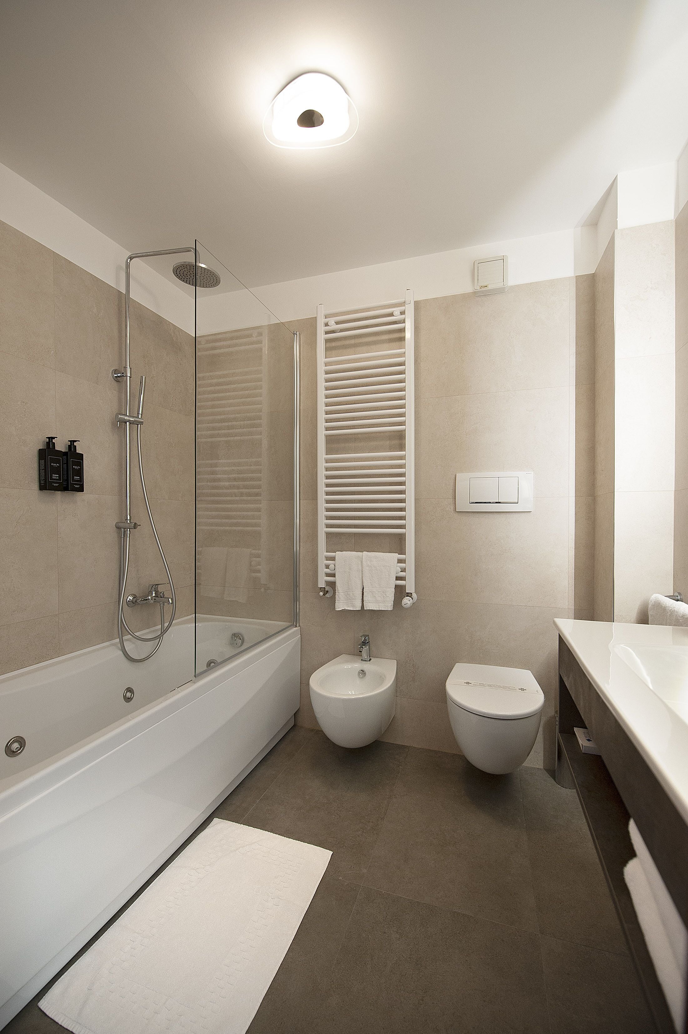 A modern bathroom with a glass-enclosed shower, a standalone sink, and a toilet.