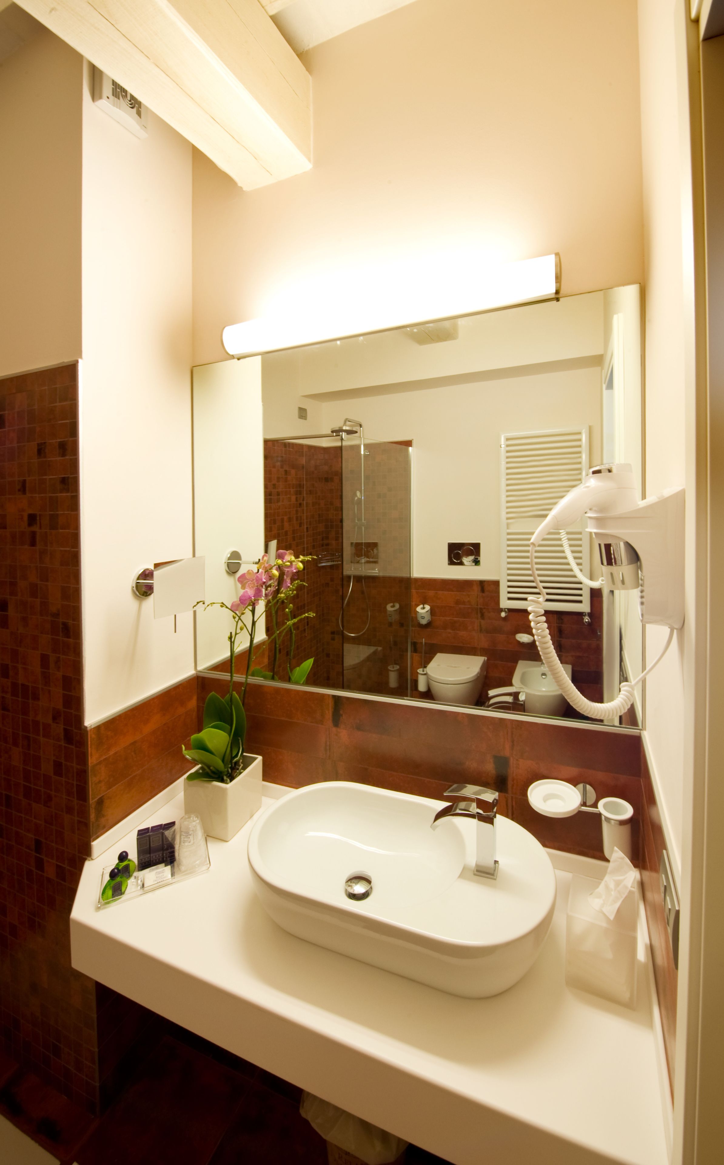 Une salle de bain moderne avec un grand miroir, un lavabo et une douche.