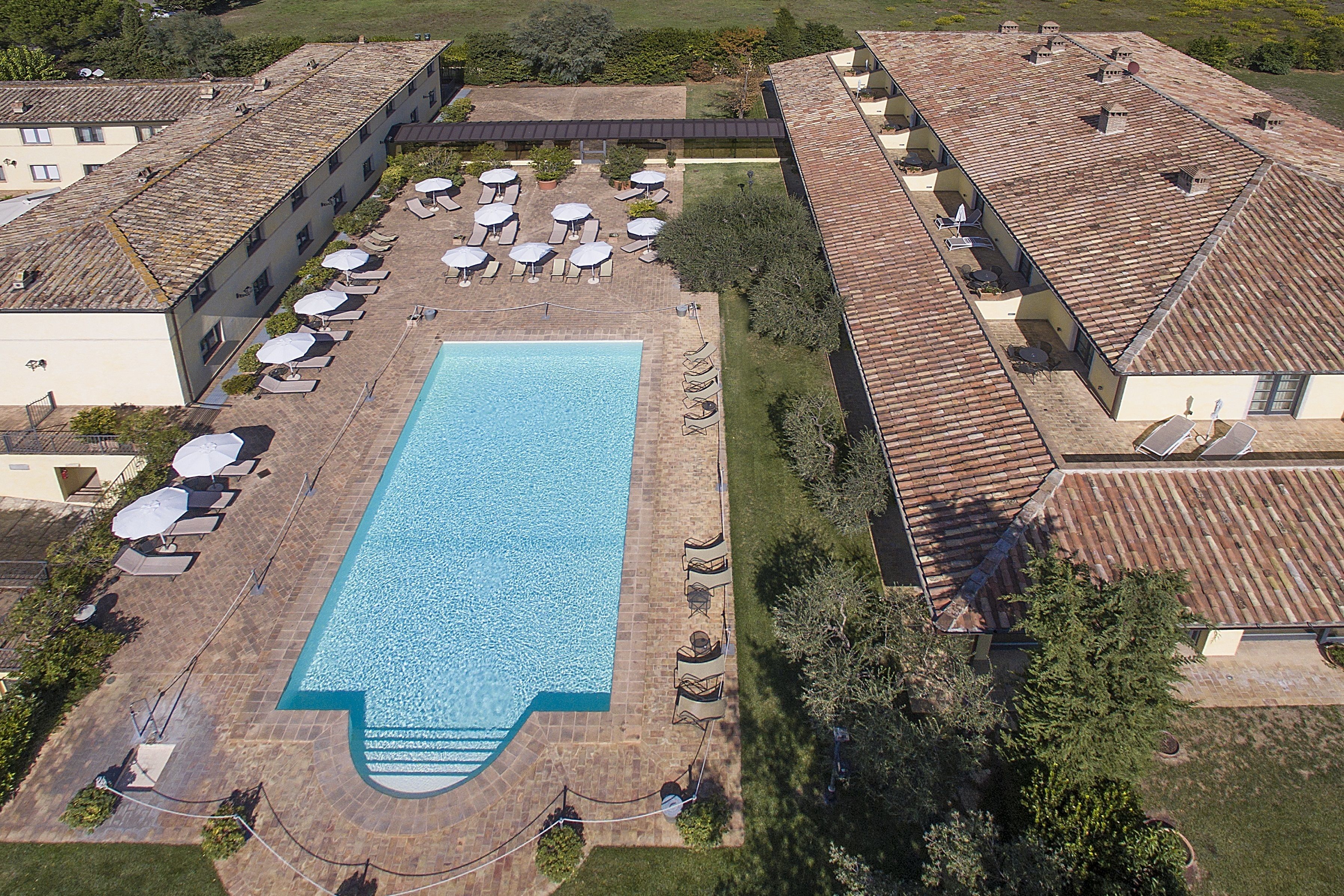 An aerial view of a hotel with a swimming pool, sun loungers, and outdoor seating areas.