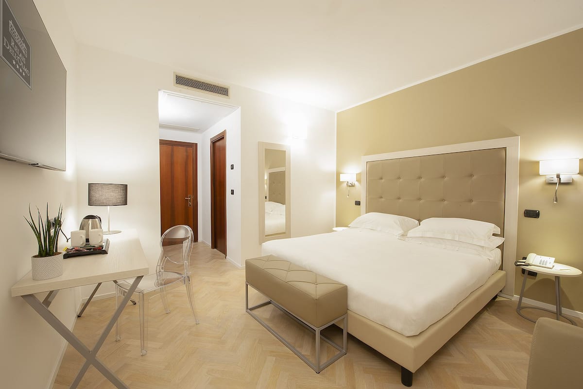 Habitación de hotel moderna con una cama grande, una mesita de noche y un escritorio pequeño con una silla.