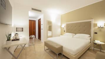 Une chambre d’hôtel moderne avec un grand lit, une table de chevet et un petit bureau avec une chaise.