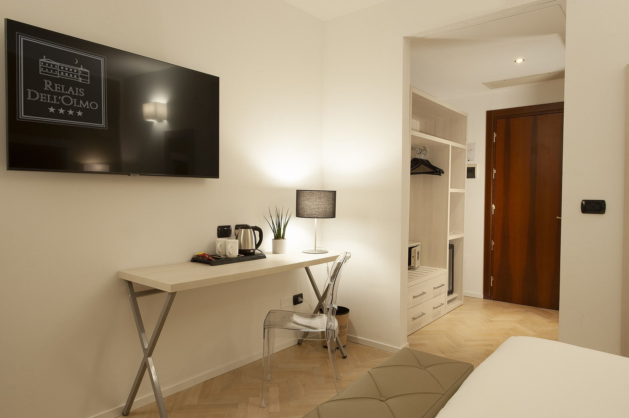 Habitación de hotel con escritorio, silla, televisor y armario.