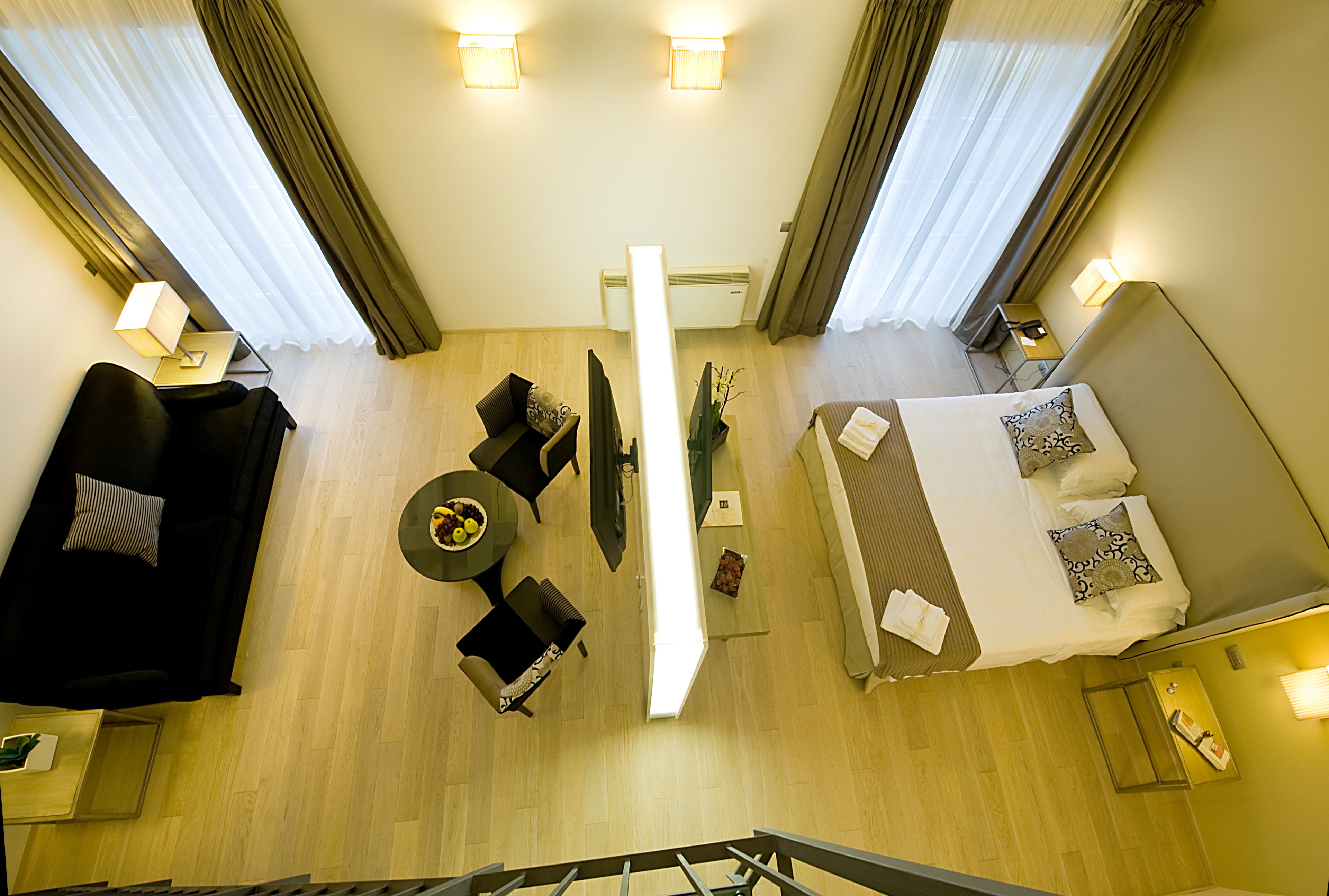 Ein Hotelzimmer mit Bett, Sofa, kleinem Tisch und Fernseher.