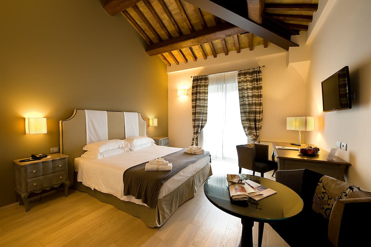 Una habitación de hotel con cama, mesitas de noche, un escritorio y una silla.