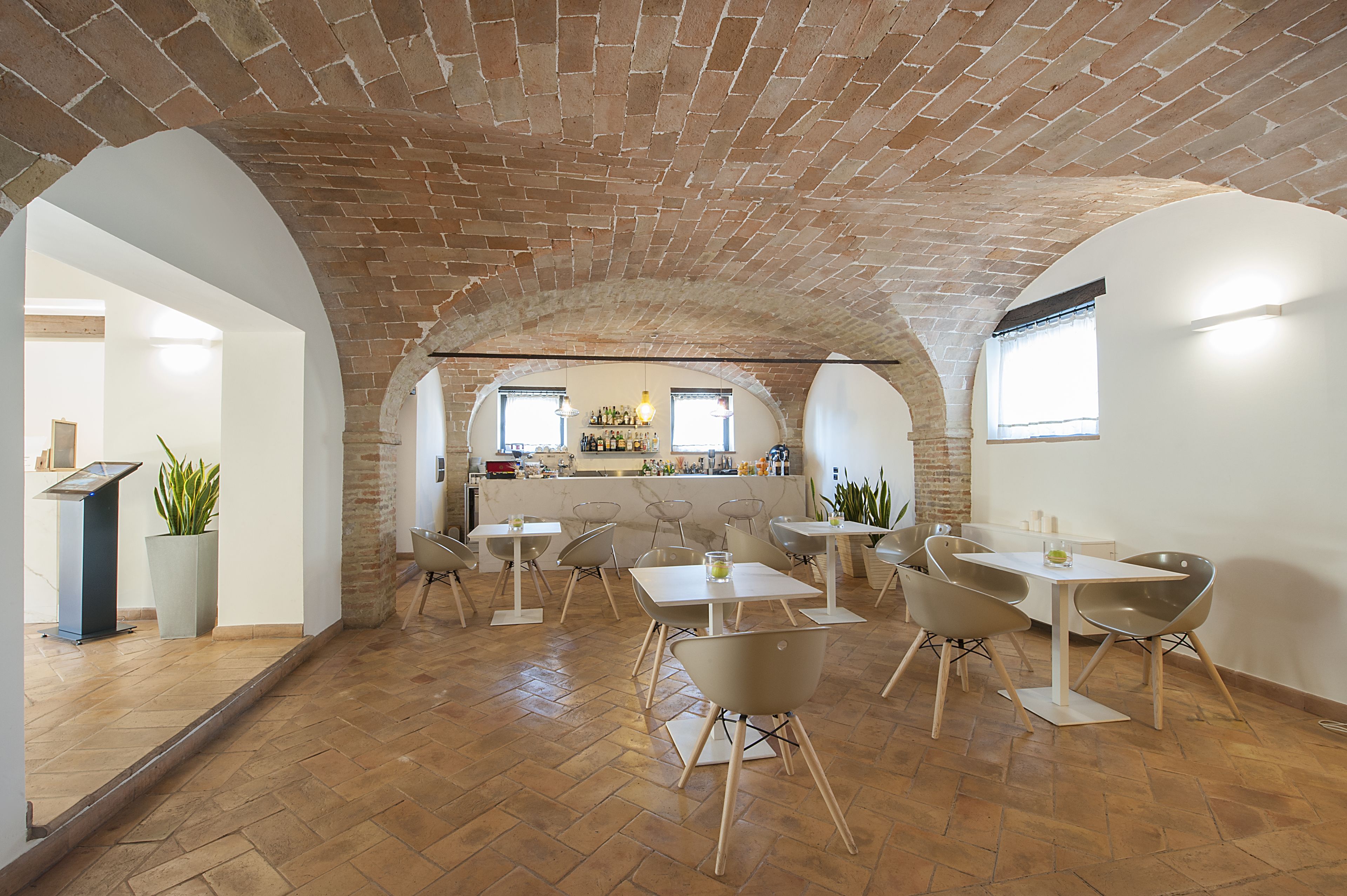 A spacious dining area with brick arches, modern tables, and chairs.