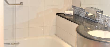 Une salle de bain avec une baignoire, un lavabo, un miroir et un porte-serviettes.