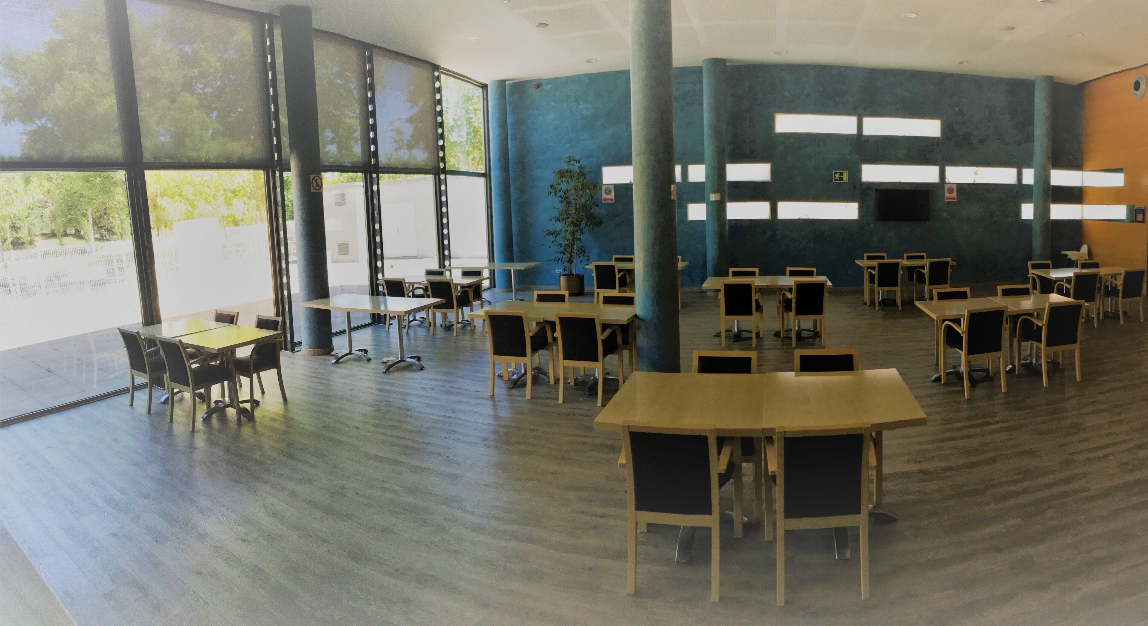 A spacious indoor area with multiple tables and chairs arranged for dining or meetings.