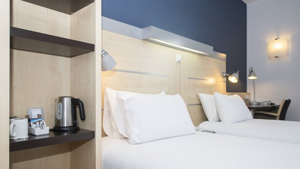 A hotel room with two beds, a coffee maker, a kettle, and a desk with a lamp. - Holiday Inn Express Barcelona - Molins de Rei by IHG (Molins de Rei)