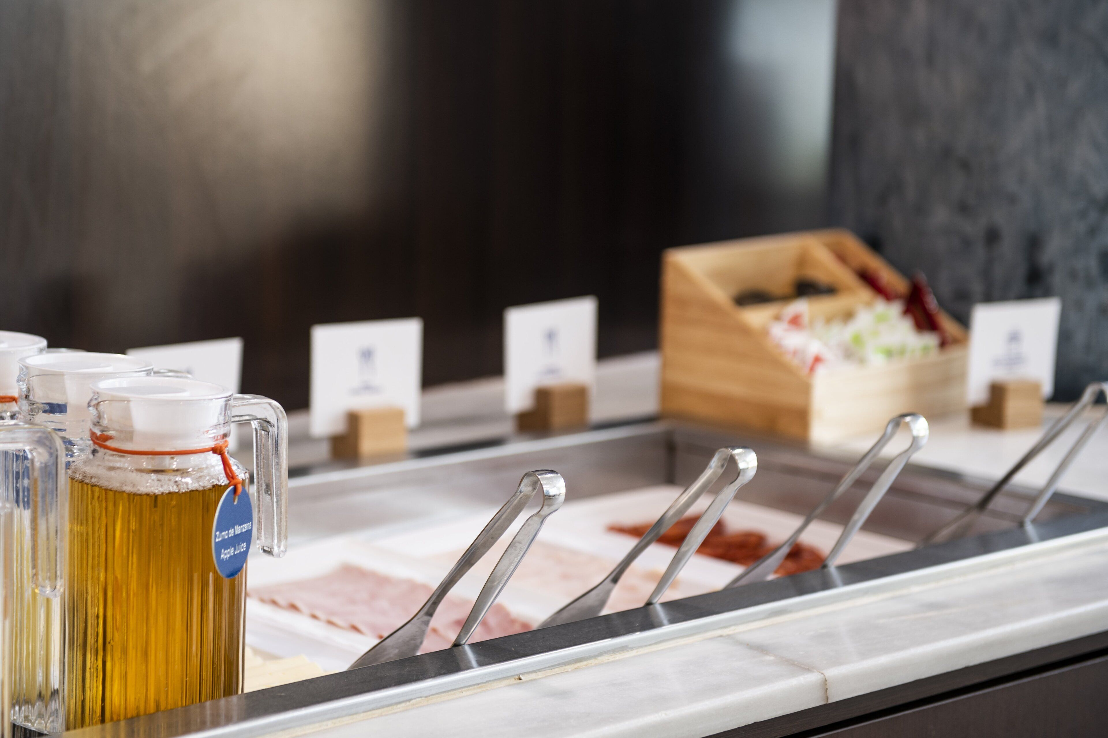 A buffet setup with a beer tap, tongs, and a wooden box in the background.