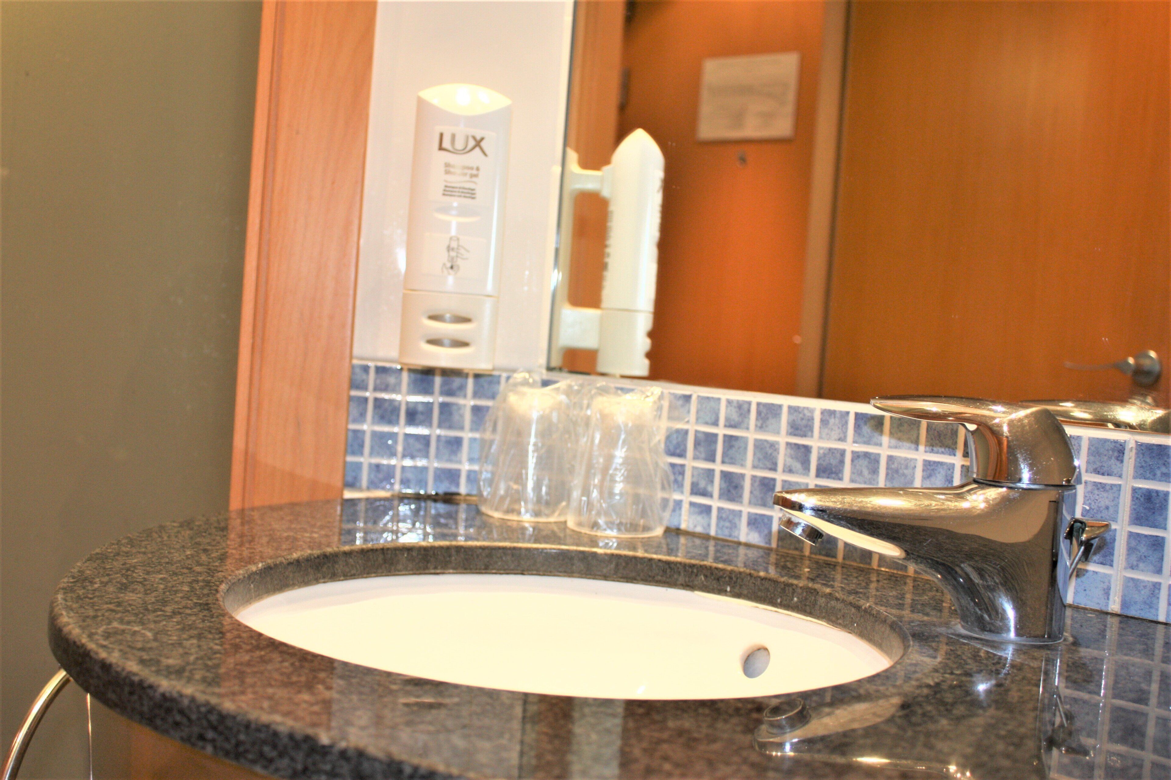 A bathroom sink with a mirror, a faucet, and a soap dispenser.