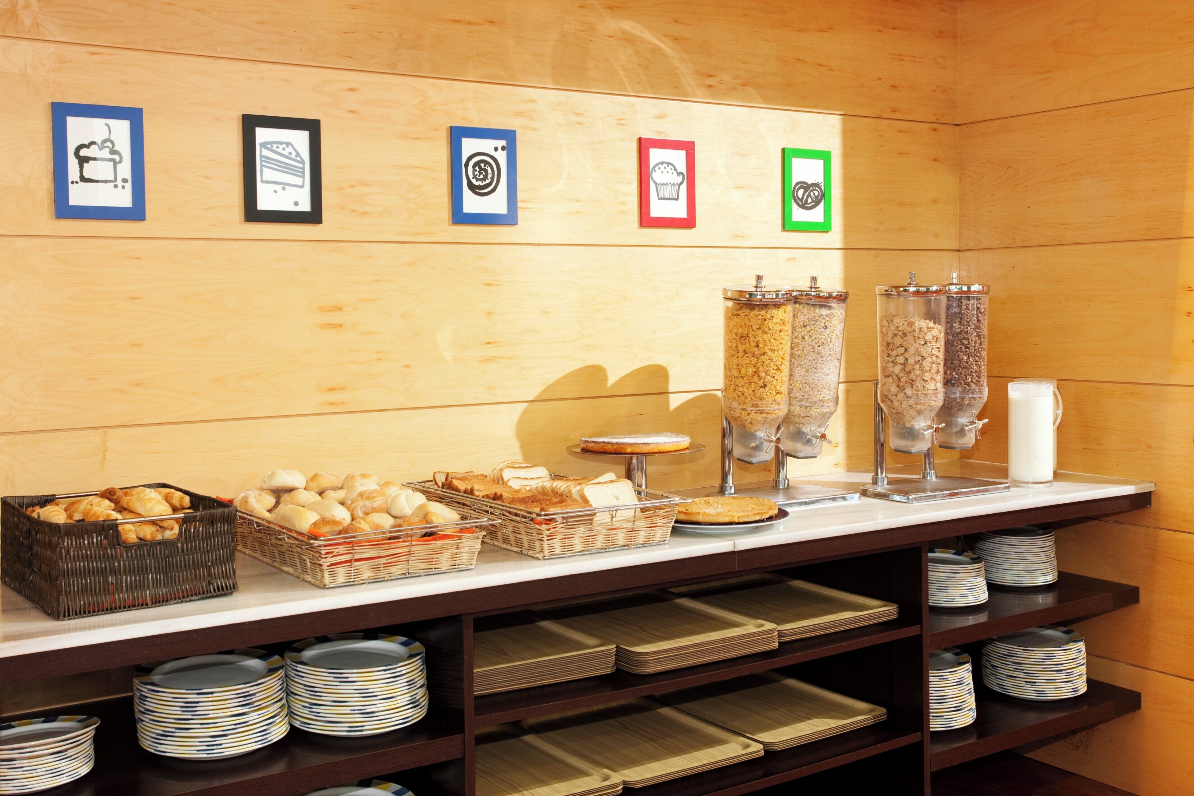 A breakfast buffet with various food items and a wall with framed pictures.