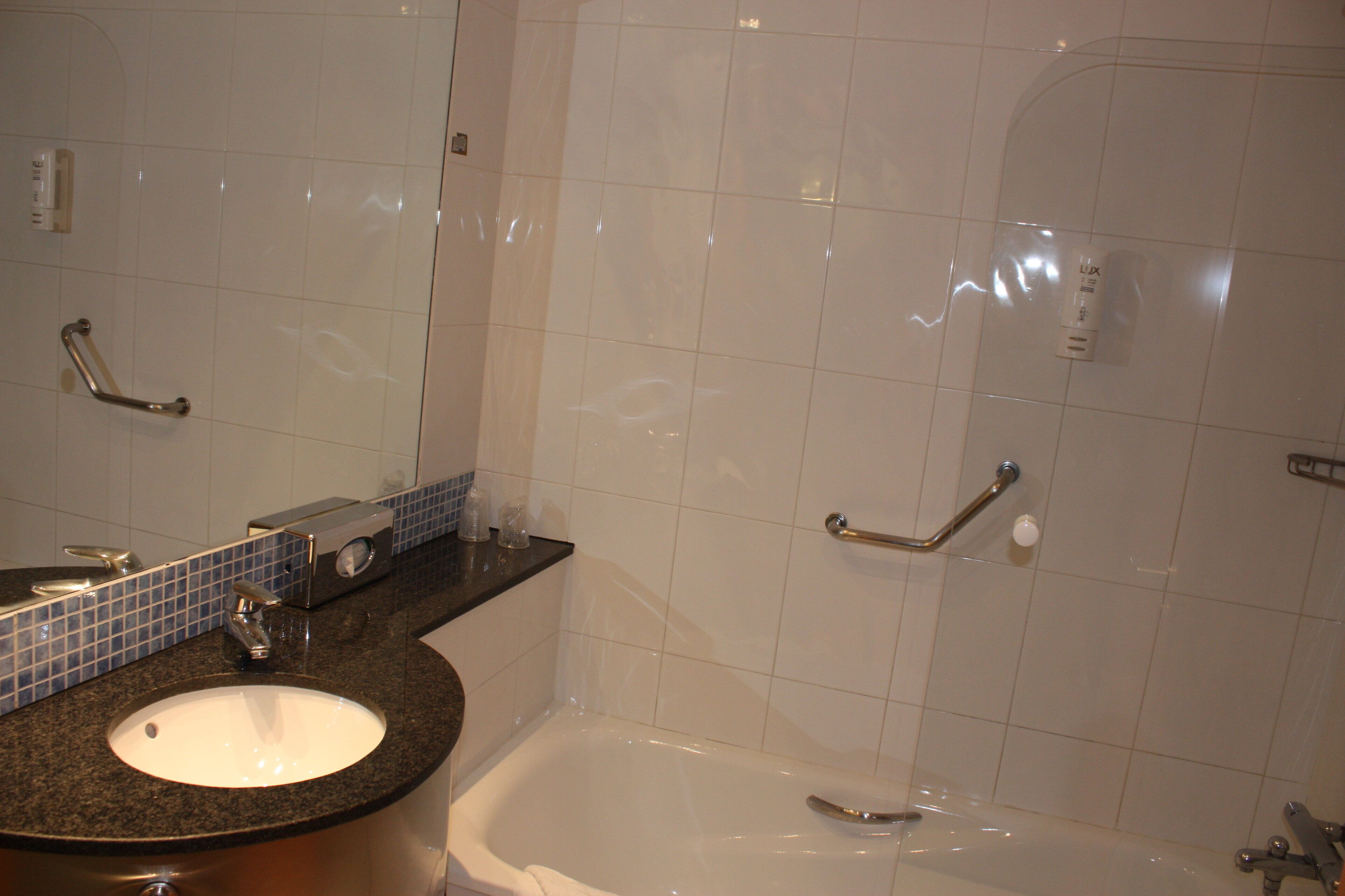 Un baño con lavamanos, espejo y bañera.