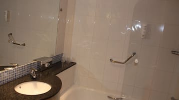 Un baño con lavamanos, espejo y bañera.
