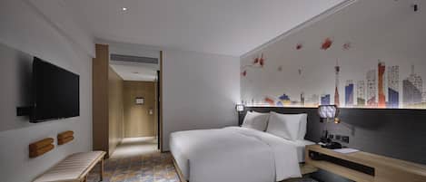 Een hotelkamer met een bed, een televisie, een bankje, een bureau en een muur met een stadsgezicht als muurschildering.